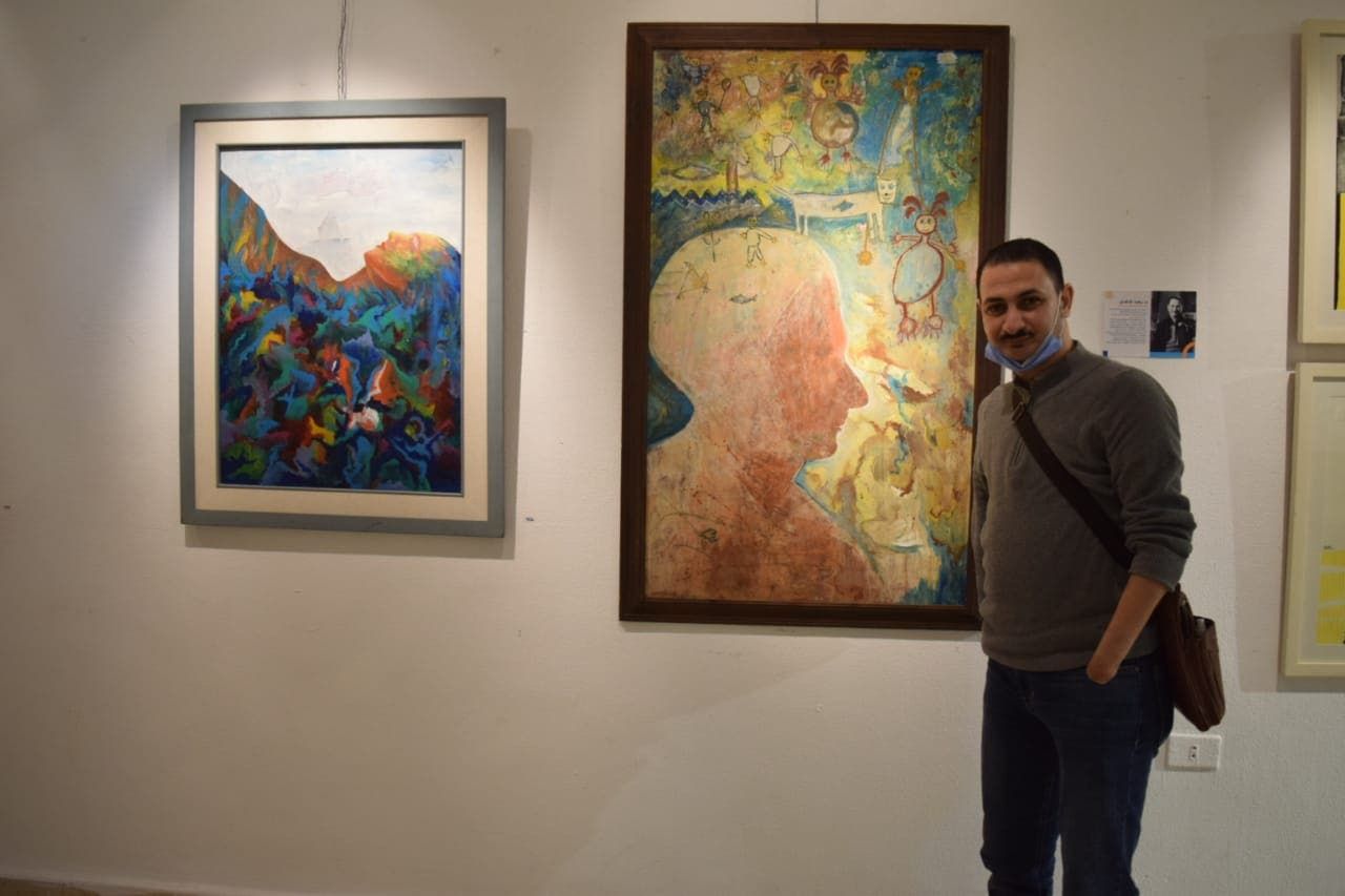 الفنان رضا فضل بجانب لوحاته